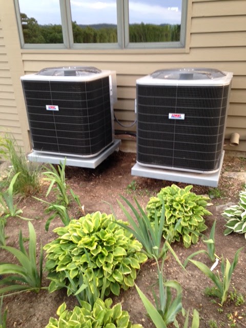 Two new air conditioning condensers on pads beside a house