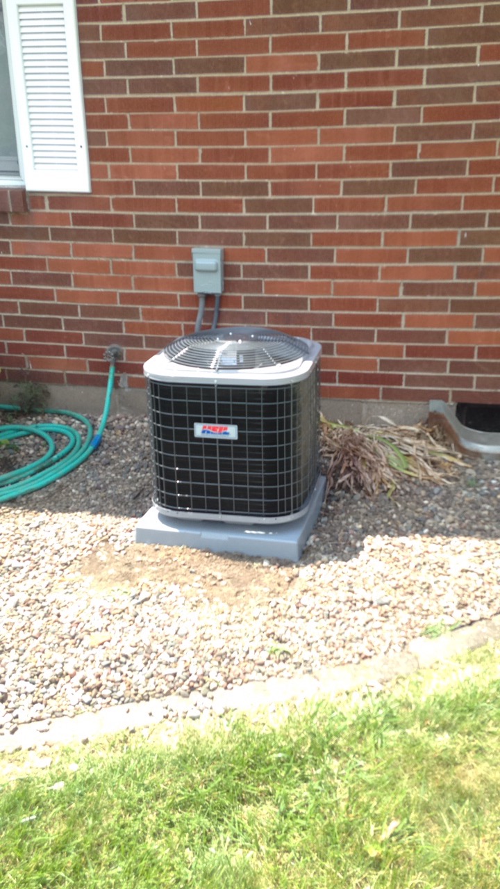 New air conditioning condenser installed by ProTech beside a brick home