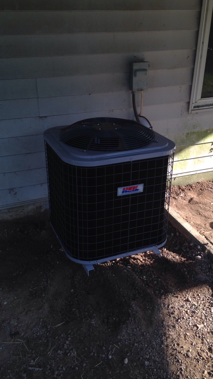 Newly installed air conditioning condenser beside a home